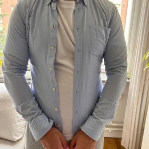 Ljusblå skjorta från Boomerang S - Snygg ljusblå skjorta från Boomerang i 100% ekologisk bomull. Skjortan har lång ärm, bröstficka och klassisk knappstängning. Trim fit-modell som sitter snyggt och stilrent. Perfekt för dig som gillar en clean och enkel look.