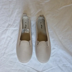 Beige tygskor från Alley, stl 40 - Snygga och enkla beige tygskor från Alley i storlek 40. Skorna har en rund tå, platt vit sula och är tillverkade i bomullstyg. Perfekta för vår och sommar när du vill ha en clean och stilren look. Nypris i butik just nu är 200 kr