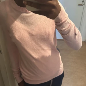 Ljusrosa stickad tröja - Säljer en ljusrosa stickad tröja med rund halsringning och långa ärmar. Perfekt för dig som gillar en enkel och stilren look. Den där svarta pricken är från spegeln så ni vet! Inte på tröjan