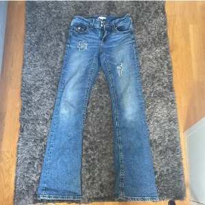 Blå bootcut jeans Gina Tricot 164 - Snygga blå bootcut jeans från Gina Young i storlek 164. Jeansen har slitna detaljer och hål framtill för en trendig look. Klassisk femficksmodell med ljus tvätt och kontrastsömmar. Perfekta för dig som gillar en avslappnad och cool stil. Har gjort hålen själv och dem är bra skick kanske lite slitna längst ner men inget man tänker på o kan skicka bilder skriv för frågor eller bilder💕