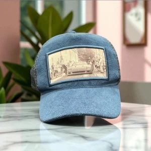 Blå keps från Weeker med bilmotiv - Snygg blå keps från Weeker med mesh på sidorna och baksidan. Framtill finns en stor patch med ett retroinspirerat bilmotiv i beige toner. Kepsen har böjd skärm och cool streetkänsla, perfekt för dig som gillar bilar och unik stil.