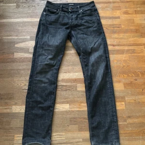 Svarta jeans från Jack & Jones - Snygga svarta jeans från Jack & Jones med klassisk femficksdesign och regular fit. Jeansen har en mörk tvätt med en svag fade. Tillverkade i mjukt denimtyg som sitter skönt hela dagen. Byxorna är ny köpta och har används bara någon gång. Ny pris 900kr.