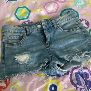 Blå jeansshorts från LAB Industries - Snygga blå jeansshorts från LAB Industries med slitna detaljer och fransig kant. Klassisk femficksmodell med dragkedja och knapp. Perfekta för sommaren och ger en cool, avslappnad vibe. Tillverkade i hållbar denim.