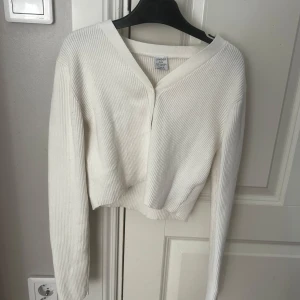Vit ribbad kofta  - Säljer en stilren vit ribbad kofta från Lindex. Koftan har en v-ringad design med knappar framtill och är croppad för en modern look. Perfekt för lager-på-lager-stilen🎀🎀