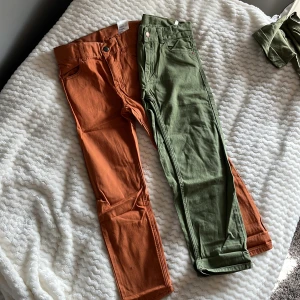 Orange och gröna byxor från H&M - Två par byxor från H&M i snygga färger. Ett par i orange och ett i grönt, båda med normal passform och midwaist. 