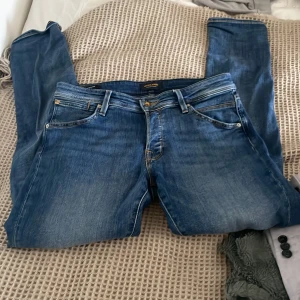 Blå slim fit jeans - Snygga blå slim fit jeans från Jack & Jones, modell Glenn. De har en klassisk femficksdesign och en bekväm passform. Perfekta för en stilren look. Ny utan prisslapp 
