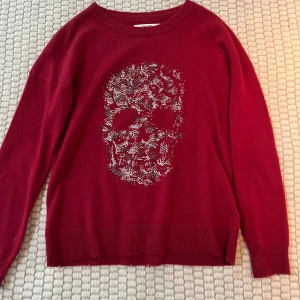 Röd tröja med dödskallemönster från Zadig voltaire - Snygg röd tröja med ett coolt dödskallemönster i silver på framsidan. Tröjan har långa ärmar och en rund halsringning. Perfekt för att ge din outfit en edgy touch.