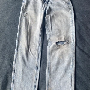 Ljusa jeans med slitningar - Snygga ljusa jeans med slitningar på låren för en trendig look. De har en klassisk femficksdesign och en bekväm passform. Perfekta för en avslappnad stil.
