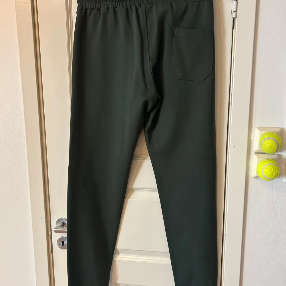Snygga gröna mjukisbyxor från Prada med elastisk midja och dragsko. Byxorna har en bakficka och en diskret logotyp på framsidan. Perfekta för en avslappnad stil med en touch av lyx. Dom passar även dig som har M. Farkut & Housut.