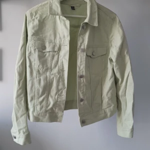 Mintgrön jeansjacka från H&M - Säljer en mintgrön jeansjacka från H&M. Jackan har en klassisk design med knappar framtill och två bröstfickor med lock. Fickor både på insidan och utsidan! 😍 Små ljusgrå märken på ena ärmen som säkert går bort med lite fläckborttagning, men utöver det är den sparsamt använd! 100% bomull. Färgen är mer färgglad på riktigt än på bilderna