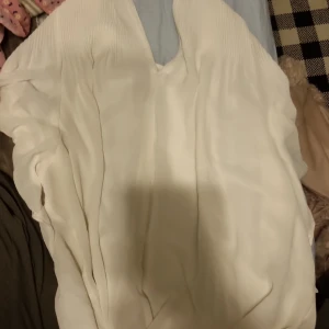 Vit klänning från H&M - Säljer en elegant vit klänning från H&M med v-ringad design. Klänningen har en mjuk och flödande passform, perfekt för sommarens alla tillfällen. Den är tillverkad i ett lätt och bekvämt material.