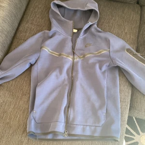 Blå hoodie från Nike - Säljer en stilren blå hoodie från Nike med dragkedja och huva. Jackan har långa ärmar och en diskret logga på bröstet. Inga hål eller liknande.🙌