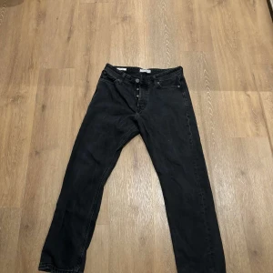 Svarta jeans från Jack & Jones - Säljer ett par svarta jeans från Jack & Jones med en loose fit. De har en klassisk femficksdesign och knappar i gylfen. W31 L32