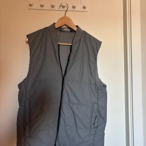 Grå väst från Zara - Säljer en stilren grå väst från Zara. Västen har en dragkedja framtill och är perfekt för lager-på-lager under kyligare dagar. Enkel och modern design som passar till många olika outfits.