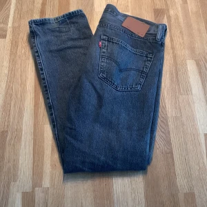 Levis 501 jeans i svart  - Klassiska Levis 501 jeans i svart. De har en rak passform och är tillverkade i slitstarkt jeanstyg. Perfekta för en tidlös stil.