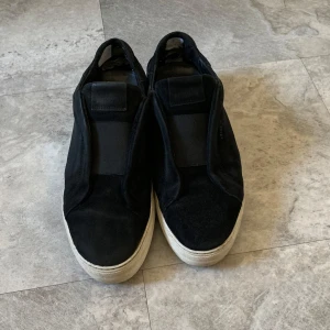 Svarta Arigato laceless skor - Feta arigato laceless skor i bra skick, de är svarta med vit sula. Storleken är 44. Det finns dock problem med sulan som har hål men kan fixas med lim därav priset. Nypris ligger på runt 2 tusen men säljer för endast 749!