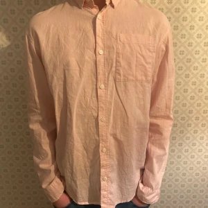 Ljusrosa linne skjorta med bröstficka - Säljer en stilren ljusrosa linne skjorta med knappar och en praktisk bröstficka. Skjortan har långa ärmar och är perfekt för en avslappnad men ändå uppklädd look. Storlek 170 motsvarande XS. Nypris 399kr. Hör av dig om du undrar något mvh Levi!