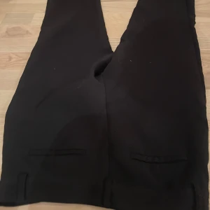 Svarta kostymbyxor - Snygga svarta kostymbyxor med en klassisk design. Byxorna har en rak passform och passar till mycket olika outfits men de saknar en knapp på insidan som tillhör där man knäpper byxorna men de funkar ändå