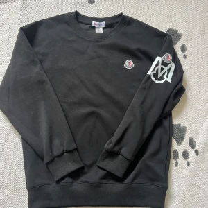 Svart sweatshirt från Moncler - Säljer en stilren svart sweatshirt från Moncler med deras ikoniska logga på bröstet och ärmen. Tröjan har långa ärmar och en rund halsringning. Perfekt för en casual look. Helt ny. Kan sänka mig rätt mycket vill få den såld. 