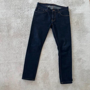 Mörkblå jeans från Nudie Jeans - Snygga mörkblå jeans från Nudie Jeans med klassisk femficksdesign och kontrastsömmar. Perfekta för en stilren look. De har en rak passform och är tillverkade i högkvalitativt denim. W31. Hör av dig om du har någon fundering mvh Levi!