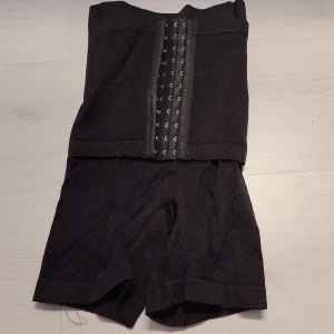 Svart shaping trosa med korsett xs/s - Säljer en svart shaping trosa med korsett i samma hyskknäppning framtill. Den är designad för att ge stöd och form åt midjan. Perfekt för att skapa en slimmad siluett under kläderna. Kommer i storlek XS/S och är lätt att justera för bästa passform.          XS/S 56-58 cm