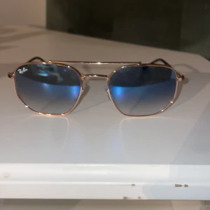 Solglasögon med blå spegelglas från Ray-Ban - Snygga solglasögon från Ray-Ban med blå spegelglas och en tunn guldfärgad metallram.