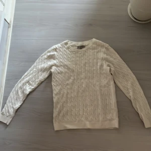 Vit kabelstickad tröja Basic You - Säljer en vit kabelstickad tröja från Basic You i storlek S. Tröjan är gjord av ekologisk bomull och har ett klassiskt mönster med struktur. Rund hals och långa ärmar gör den perfekt för kyliga dagar. Enkel och clean stil som funkar till jeans eller kjol.