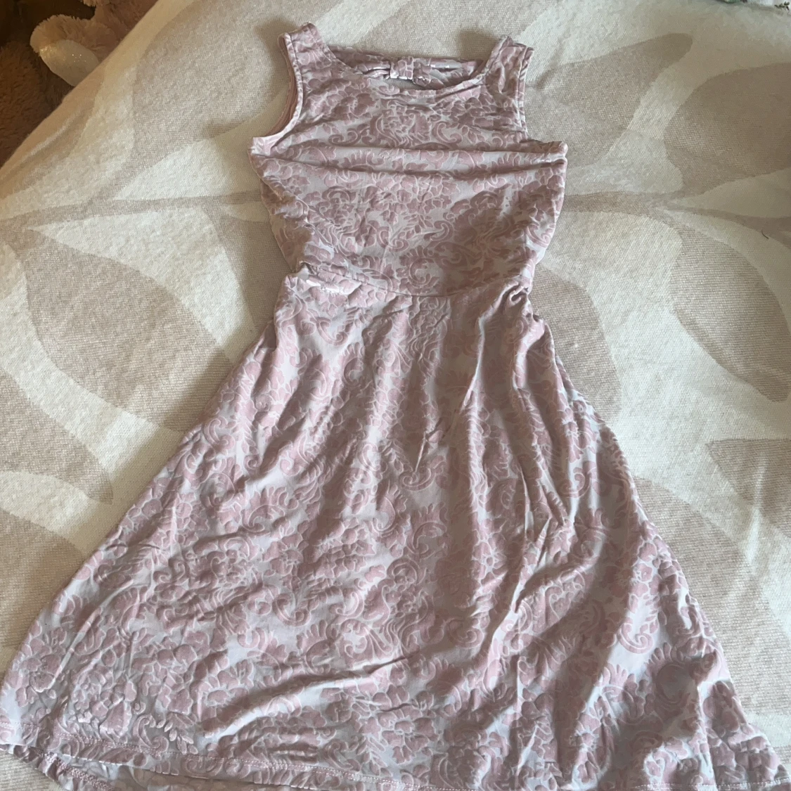 Ljusrosa klänning med rosett och mönster