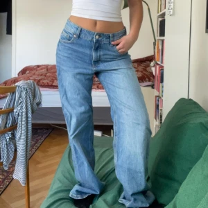 Blåa wide jeans med låg midja - Säljer ett par ljusblå jeans med låg midja och wide fit. Jeansen har klassisk femficksdesign, raka ben och är tillverkade i jeansmaterial. Perfekta för en avslappnad och trendig look.