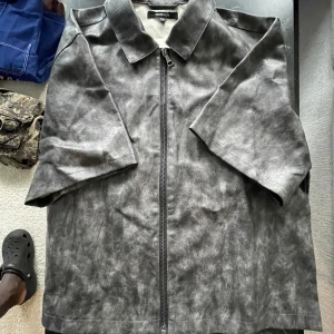 Svart skinnjacka från Monki Men - Säljer en svart skinnjacka från Monki Men med rak passform och dragkedja framtill. Jackan har klassisk krage och halvkort ärm, vilket ger en cool och modern vibe. Perfekt för dig som vill sticka ut med en edgy look.