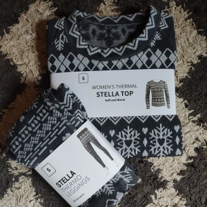 Varmt pyjamas set - Säljer ett matchande set med ett par leggings och en långärmad tröja. De kan användas som en varm pyjamas under kalla vinter nätter, som en mysig hemma outfit när julen närmar sig eller som ett tjockt underställ. Kläderna är mörkgrå med ett vintrigt mönster i vit över hela plaggen.