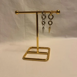 Chunky örhängen med konformad detalj - Säljer ett par coola chunky örhängen i silver och guld med stora ringar och konformade hängen. De har en edgy vibe och passar perfekt om du gillar statement-smycken. Materialet är metall och designen är modern med kontrasterande färger.