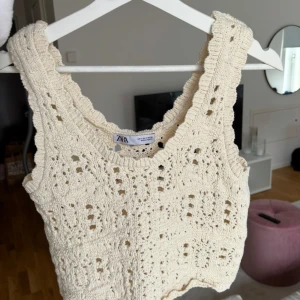 Beige virkad linnetopp från Zara - Superfin beige virkad linnetopp från Zara med breda axelband och snyggt hålmönster. Toppen är croppad och har en bohemisk känsla, perfekt till jeans eller kjol. Materialet är mjukt och luftigt, vilket gör den skön att bära under varma dagar.