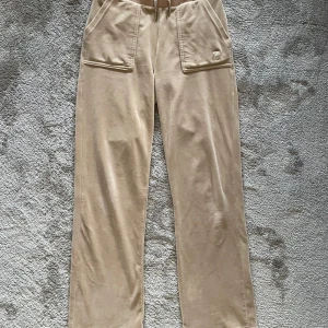 Beige Juicy Couture - Snygga beige mjukisbyxor från Juicy Couture i storlek XS. Köpt för några år sen men knappt använda. Sömmen har dock gått upp på ena bakfickan (se sista bilden). Även uppsydda så de passar folk runt 160-165 kanske. 