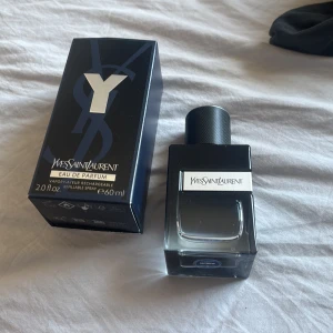 Yves Saint Laurent Y EdP 60 ml - Y EdP från Yves Saint Laurent är en stilren parfym i en mörkblå och transparent glasflaska med svart lock och silverdetalj. Flaskan har en fyrkantig form och rymmer 60 ml. Kommer med originalförpackning i matchande mörkblå design. Nästan helt full nypris ca 1200kr 