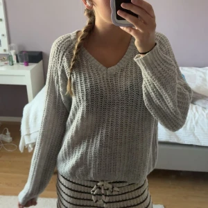 Grå stickad v-ringad tröja - Säljer en chill grå stickad tröja med v-ringad hals. Tröjan har en loose passform och långa ärmar, perfekt för att mysa i under kyliga dagar. Enkel och stilren design som funkar till det mesta. Fråga gärna om du vill veta mer om storlek!