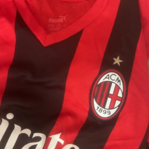 AC Milan fotbollströja Puma xs - Säljer en officiell AC Milan fotbollströja från Puma i storlek xs. Tröjan har klassiska röda och svarta vertikala ränder, klubbmärke med stjärna på bröstet och v-ringad krage. Materialet är lätt och andas, perfekt för match eller träning.