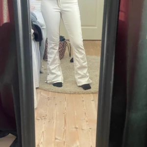 Vita bootcut jeans med knappar - Säljer ett par vita jeans med bootcut passform och snygga knappar längs nedre delen av benen. Storlek 164, 13-14, jag på bilden är 160. Skriv om ni har frågor💕