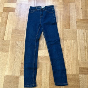 Mörkblå  jeans från Dobber - Snygga mörkblå jeans från Dobber med klassisk femficksdesign och smal passform. Jeansen har kontrastsömmar, knapp och dragkedja framtill samt läderpatch med logga bak. Perfekta för dig som gillar en clean och stilren look.