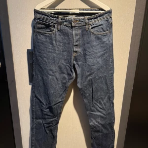 Blå jeans Relaxed Chris, storlek 33 - Säljer ett par klassiska blå jeans från Relaxed Chris i storlek 33. Modellen har avslappnad passform med raka ben och fem fickor. Jeansen har gul kontrastsöm och är tillverkade i slitstarkt denim. Perfekt för dig som gillar en chill och enkel stil.
