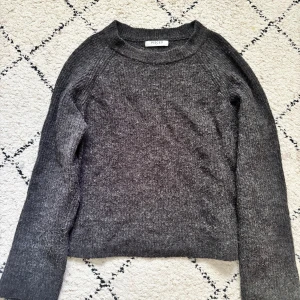 Mörkgrå stickad tröja från Pieces - Säljer en mörkgrå stickad tröja från Pieces i storlek S. Tröjan har en enkel, klassisk design med rund hals och långa ärmar. Materialet är mjukt och mysigt, perfekt för kyliga dagar. Passformen är normal och färgen är snyggt mörkgrå.