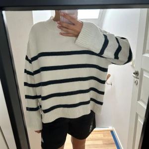 Vit och svart randig stickad tröja - Säljer en stickad tröja med breda svarta ränder på vit botten.