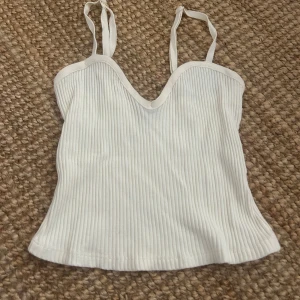 Vit ribbad linnetopp med v-ringning - Snygg vit linnetopp med ribbad struktur och v-ringad hals. 