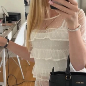 Gräddvit volangblus - Superfin gräddvit meshblus med kort ärm, volangdetaljer och prickigt mönster. Passar storlek XS.