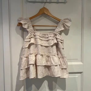 Beige volangtopp med breda axelband - Supersöt beige topp med volanglager. 