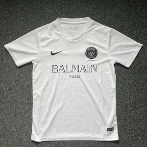 PSG Balmain Tröja - Säljer en vit PSG fotbollströja i samarbete med Balmain. Klassisk rund hals och korta ärmar. Storlek S och i Mycket bra skick. Perfekt för dig som gillar stilrena matchtröjor!