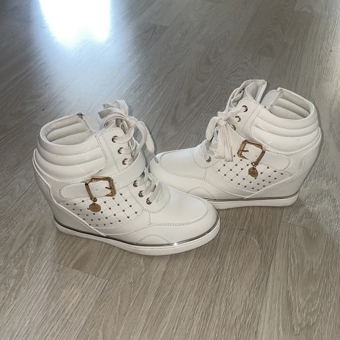 Vita sneakers med kilklack och gulddetaljer