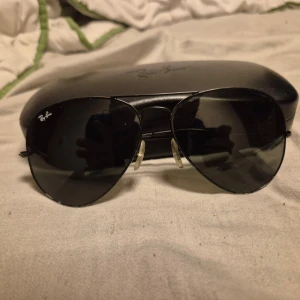 Svarta aviator-solglasögon från Ray-Ban - Klassiska svarta aviator-solglasögon från Ray-Ban med tunna metallbågar och mörka linser. Kommer med original Ray-Ban-fodral. Perfekt accessoar för en stilren look. Skit bra skick köpta 2021 för 2200