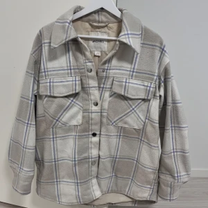 Beige rutig overshirt från Monki - Säljer en beige rutig overshirt från Monki. Den har långa ärmar och knappar framtill. Lite nopprig annars inga defekter. Hör av dig för fler bilder🩷