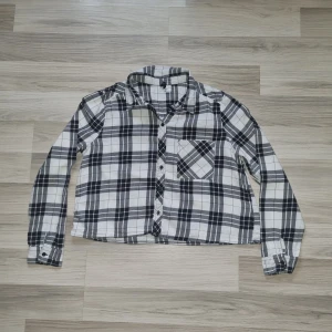 Svartvit rutig skjorta från H&M Divided - Säljer en svartvit rutig skjorta från H&M Divided i storlek 42 men är som en storlek 36. Skjortan har långa ärmar, klassisk krage, knäppning framtill och en bröstficka. Perfekt för en avslappnad och cool stil.